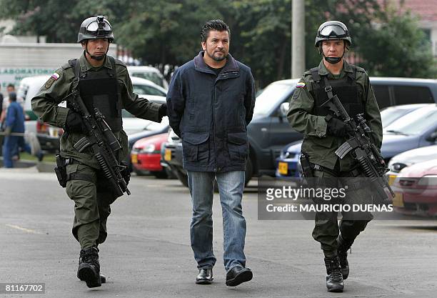 Colombian policemen escort alleged drug trafficker Gildardo Rodriguez Herrera, a.k.a "The Man of the Red Shirt", to a press conference in Bogota on...
