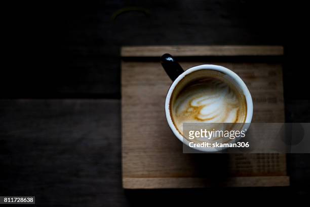 top view selective focus hot cappuccino on wooden plate with darken background - coffee machine stockfoto's en -beelden