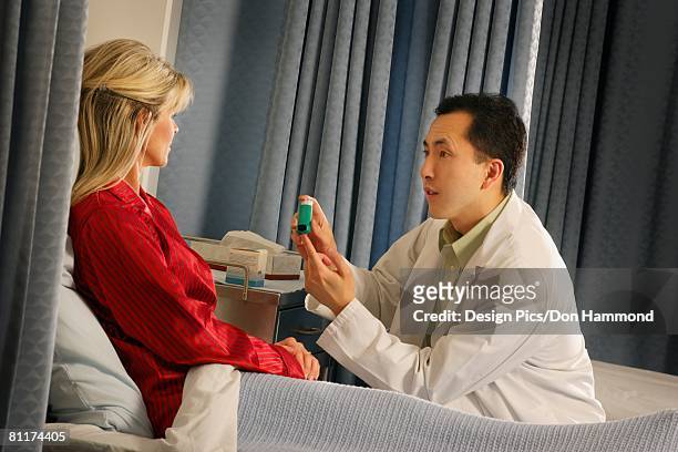 doctor instructing patient with inhaler - design pics don hammond stock-fotos und bilder