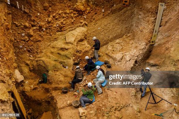 Archaeologists work at the "Sima del Elefante" dig, in the archaeological site of the Atapuerca mountain range, province of Burgos on July 10, 2017....