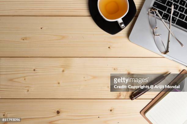 wooden table from above with laptop keyboard, green tea cup, notepad, pen and copy space - desk aerial view stock pictures, royalty-free photos & images