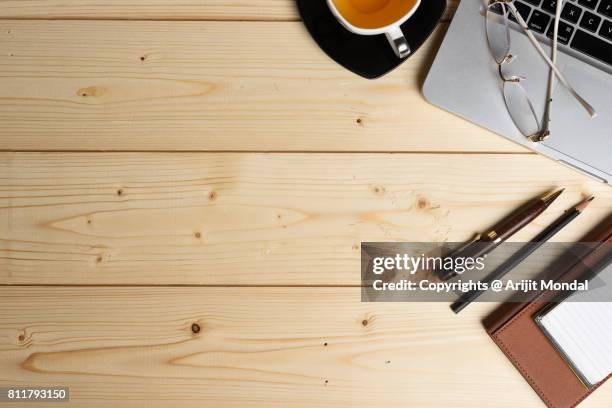 top view wooden finish table with laptop, tea cup, pen, pencil, note book and spectacle - desk aerial view stock pictures, royalty-free photos & images