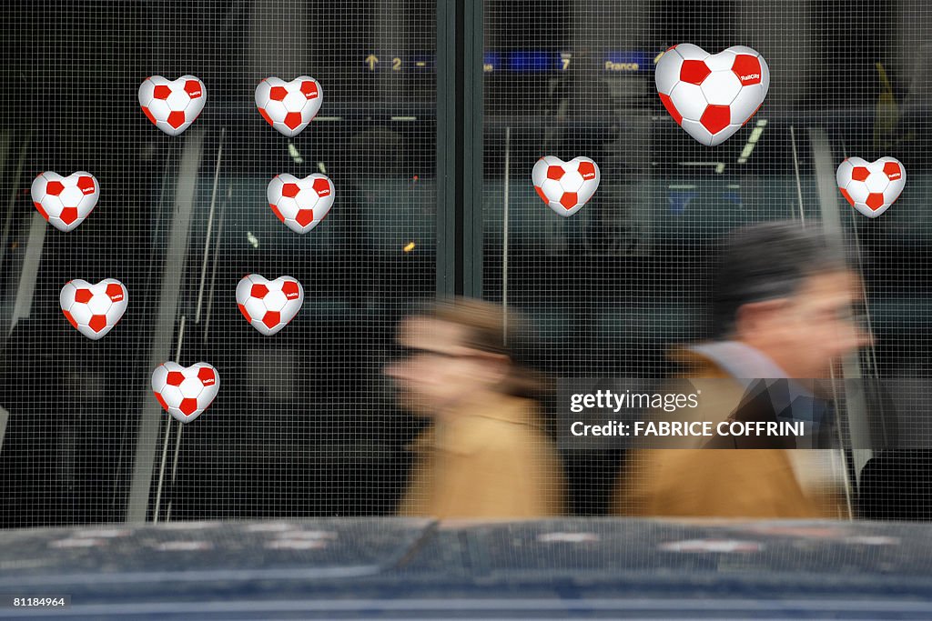 People walks by heart-shaped footballs d