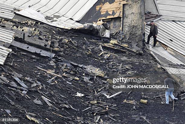 Unidentified officials survey the damage on the roof of the Berlin Philharmonic May 21, 2008 after a major fire broke out May 20 and smoke poured...