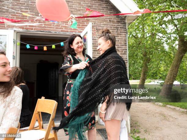 woman handing a warm shawl to a girl - 811864610,811864624,811864632,811864620,811864622,811864660,811864636,811864644,811864638,811864674,811864656,811864664,811864652,811864680,811864704,811864716,811867486,811867482,811867480,811867478 stockfoto's en -beelden