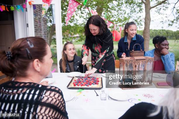 mature woman cutting fruit pie at a birthday party - 811864610,811864624,811864632,811864620,811864622,811864660,811864636,811864644,811864638,811864674,811864656,811864664,811864652,811864680,811864704,811864716,811867486,811867482,811867480,811867478 stockfoto's en -beelden