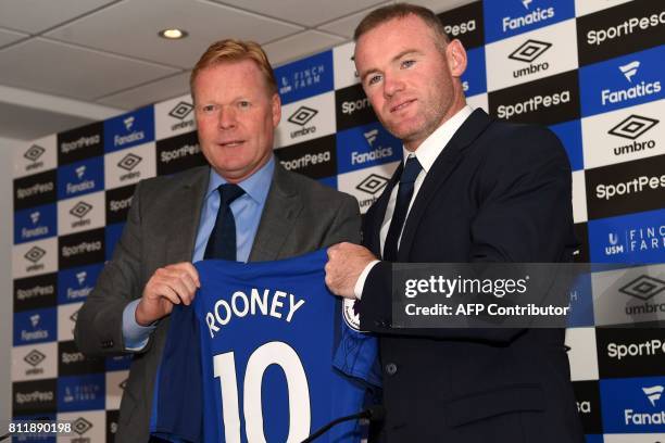 Everton's new signing, English striker Wayne Rooney poses for a photograph with his new club shirt, held by Everton's Dutch manager Ronald Koeman...