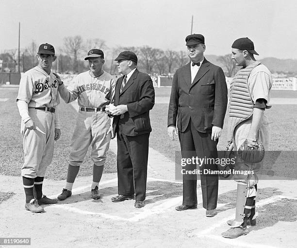 Manager Mickey Cochrane of the Detroit Tigers and manager Bill McKechnie of the Cincinnati Reds review the ground rules with umpires , George...