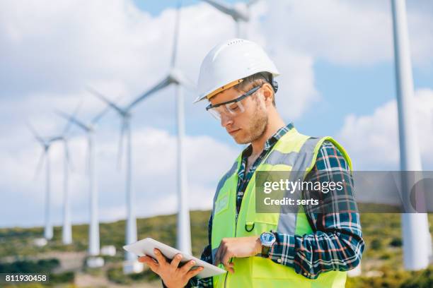 young engineer man looking and checking wind turbines at field - mill worker stock pictures, royalty-free photos & images