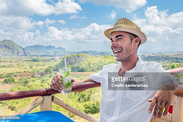 happy man holding mojito against valle de vinales - valle de vinales stock pictures, royalty-free photos & images