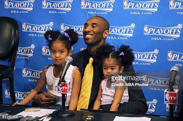 Kobe Bryant of the Los Angeles Lakers answers questions from the media while holding his daughters Natalia and Gianna, following his team's victory...