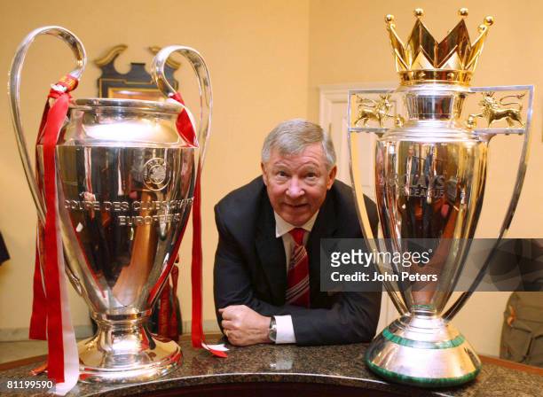 Sir Alex Ferguson of Manchester United poses with the UEFA Champions League trophy and the FA Barclays Premier League trophy after winning the UEFA...