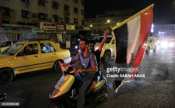 An Iraqi waves a national flag as he rides in the back of a scooter with another, while celebrating at the Tahrir Square in the capital Baghdad on...