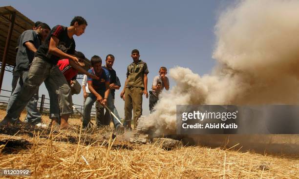 Palestinian youths attempt to extinguish tear gas fired by Israeli Defense Forces during a demonstration against the blockade on Gaza, on May 22,...