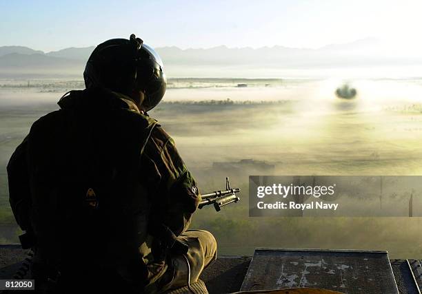 An aircrewman from 27 Squadron RAF mans the M60 mounted on the back of the tailgate of his chook as it transits the Afghan countryside in the morning...