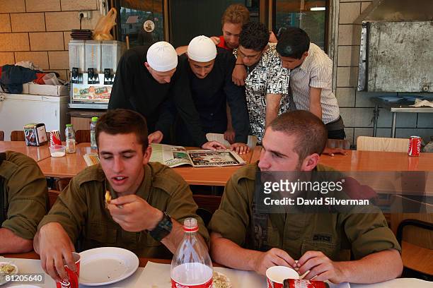 As Israeli army soldiers eat a typical Arab breakfast at a local restaurant, Druze youths pore over the sports pages of an Israeli newspaper May 22,...