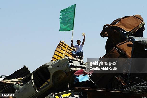 Palestinian protester stands on old cars as he holds a Hamas flag during a demonstration against the blockade on Gaza, on May 22, 2008 at the Karni...