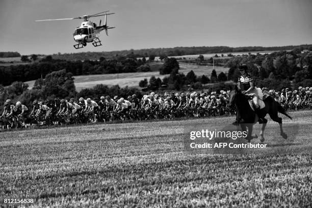 Horse rider is pictured in front of the pack riding as a media helicopter flies over the pack during the 213,5 km seventh stage of the 104th edition...