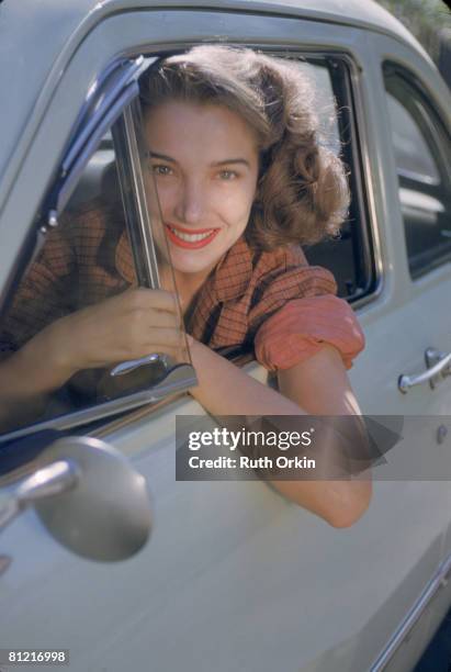 Portrait of American actress Julie Adams as she leans out of the window of a car, early 1950s.