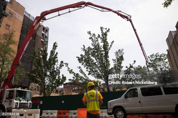 Worker monitors traffic as a pump truck sends concrete into a building site July 6, 2017 where townhouses are under construction in Brooklyn, New...