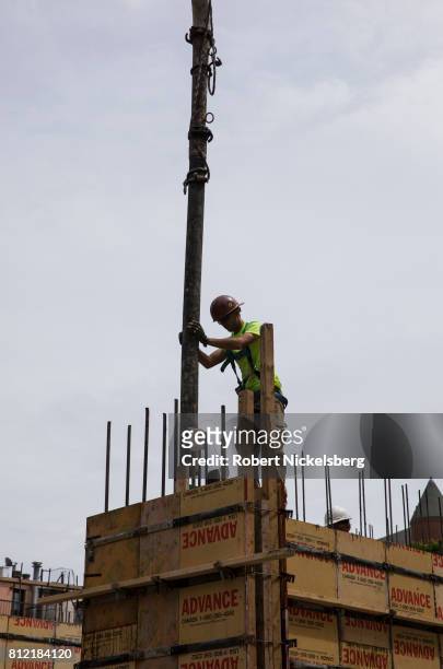Worker feeds concrete into a structural form July 6, 2017 on a building site where townhouses are under construction in Brooklyn, New York. The...