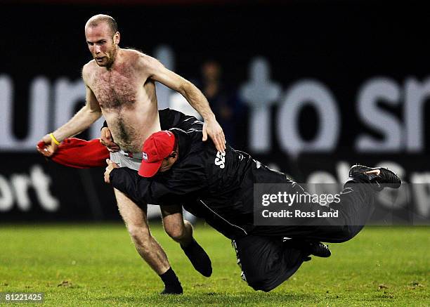 Security guard tackles a streaker during the Super 14 semi-final match between the Crusaders and the Hurricanes at AMI Stadium on May 24, 2008 in...