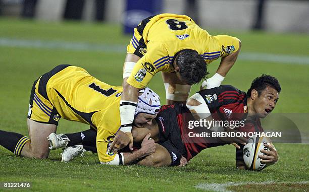 Canterbury Crusaders Casey Laulala releases the ball in a tackle as Wellington Hurricanes players Scott Waldrom and Chris Masoe try to recover the...