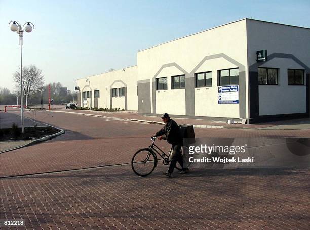 Man walks his bicycle past a newly built commercial building April 22, 2002 in the city of Auschwitz, Poland. Auschwitz, which is known for one of...