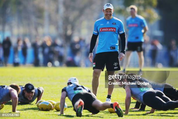 Assistant coach Brenton Sanderson looks at players performing push ups during a Collingwood Magpies AFL training at the Holden Centre on July 11,...