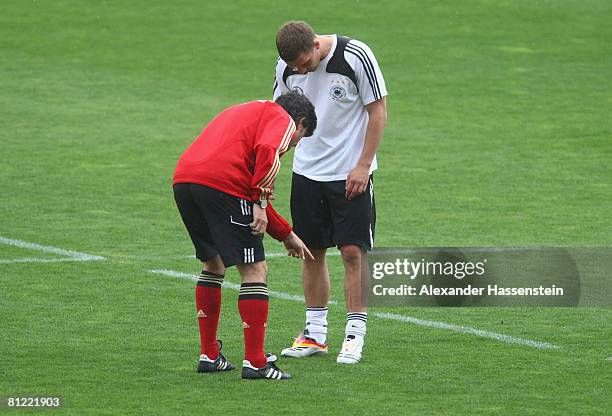 Joachim Loew, head coach of the German nationa team, looks at Lukas Podolski new soccer boots during a training session at the Son Moix stadium on...