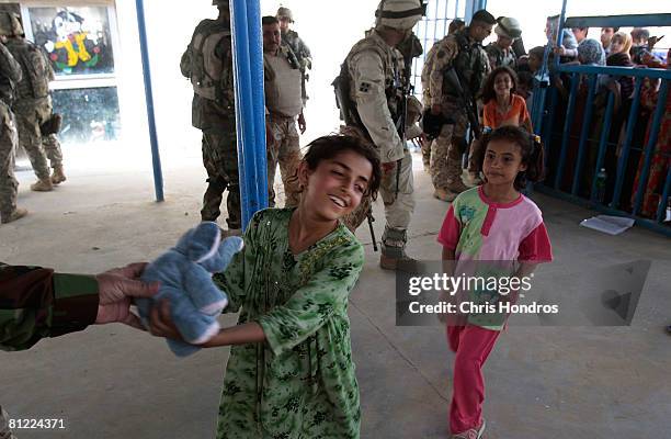 An Iraqi girl smiles as she gets a stuffed animal supplied by the 3rd Brigade Combat Team of the 4th Infantry Division of the US Army during a...
