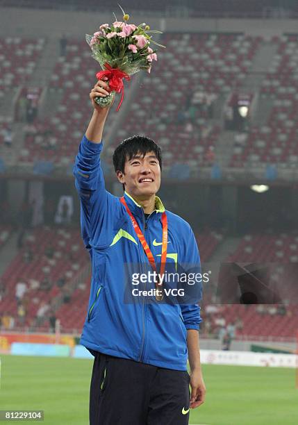 China's world and Olympic champion Liu Xiang celebrates on the winners' podium with his gold medal for the Men's 110m Hurdles final during the Good...