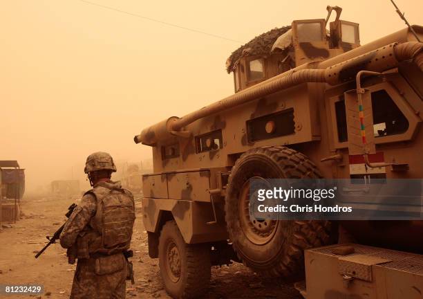 Army soldier of the 3rd Brigade Combat Team of the 4th Infantry Division stands next to an Iraqi Army armored vehicle in a deserted market area, that...