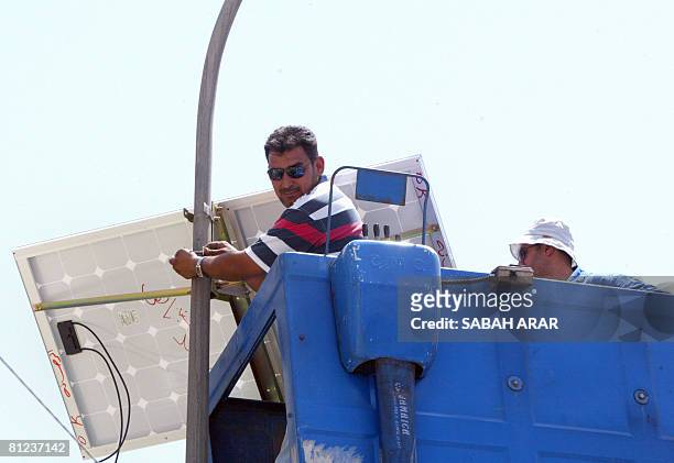 Municipal worker adjust a solar panel attached to the top of an electricity pylon along the central isle of a main road in the Karada district of...