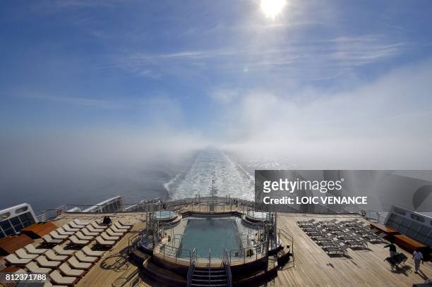 Deck stewards work next to a pool on June 28 aboard the chimney of the Cunard cruise liner RMS Queen Mary 2, sailing in the Atlantic ocean during the...
