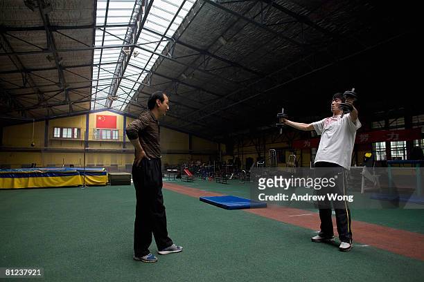 China's Olympic champion 110-meter hurdler Liu Xiang undergoes training with the help of his coach Sun Haiping at the National Training Center of...