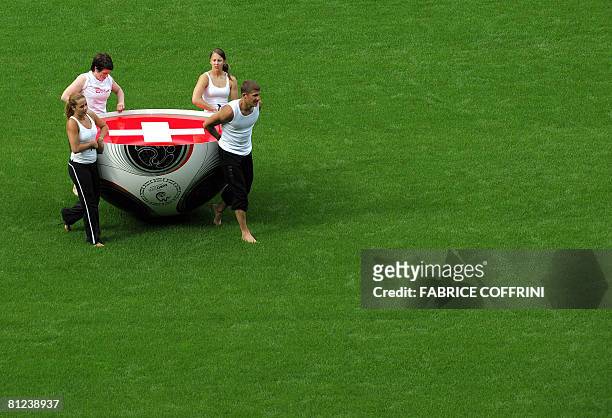 Gymnasts carry the half-part of a giant match ball of the Euro 2008 adorned with the Swiss flag during a pratice session of the Euro 2008 pre-match...