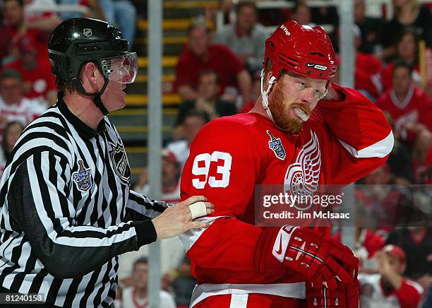 Johan Franzen of the Detroit Red Wings is helped back to the bench by linesman Jean Morin after taking a stick to the face from the Pittsburgh...