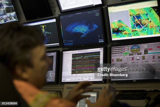 An operator watches screens showing radar scans, maps and camera images in the control room as the 'crawler' machine sucks up sediment from the...