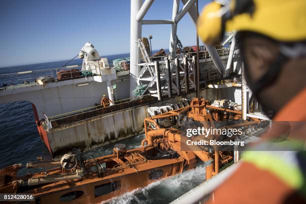 Workers watch as the 'crawler' tractor is lowered into the sea from the deck of the Mafuta diamond mining vessel, operated by Debmarine Namibia, a...