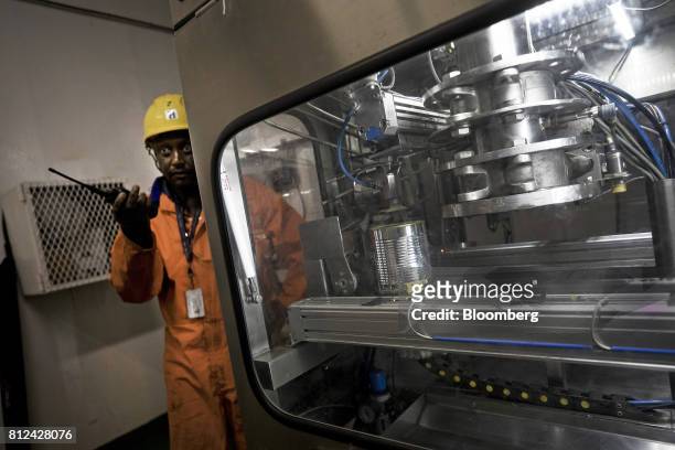 Supervisor stands on watch as a machine automatically seals diamonds sourced from the seabed in a barcoded tin can aboard the Mafuta diamond mining...