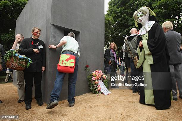 Visitors, including a transvestite, line up to peek into the window of the just-inaugurated memorial to homosexual victims of the Nazis on May 27,...