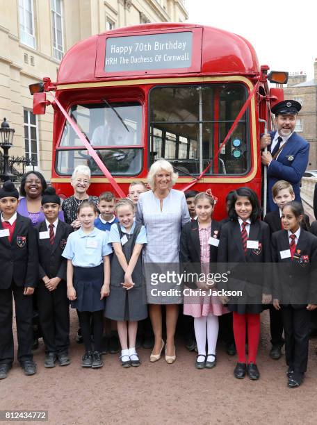 Camilla, Duchess of Cornwall poses with author Jacqueline Wilson , comedian and author David Walliams dressed as an bus conductor, school children...