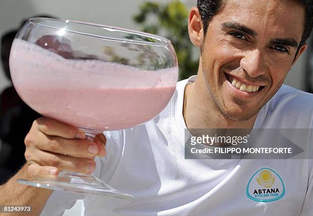 Pink jersey of the overall leader, Spain's Alberto Contador holds a cup of strawberry milkshake outside his hotel in Teglio on May 27 on the restday...