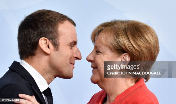 French President Emmanuel Macron is greeted by German Chancellor Angela Merkel as he arrives for a "retreat meeting" on the first day of the G20...