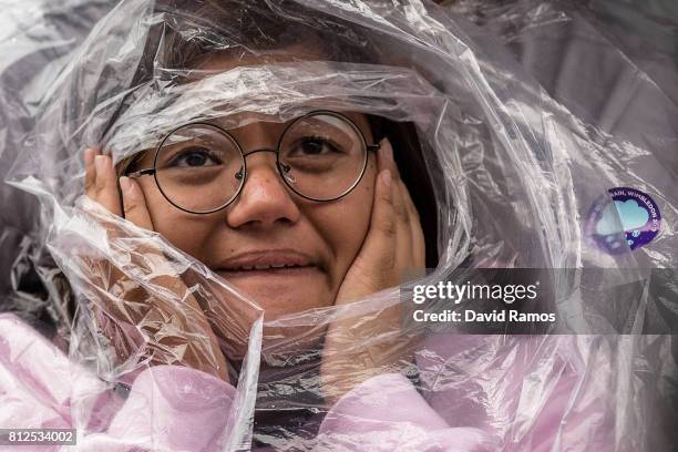 Spectator shelters from the rain on day eight of the Wimbledon Lawn Tennis Championships at the All England Lawn Tennis and Croquet Club on July 11,...