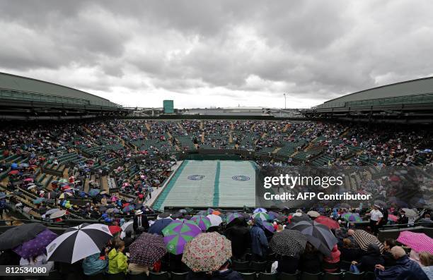 Ground staff prepare the court covers as rain stops play ahead of the women's singles quarter-final match between Spain's Garbine Muguruza and...