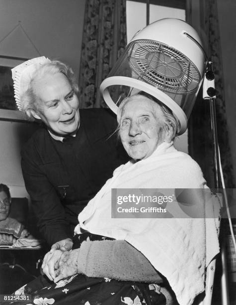 Mrs Sarah Young gets a new perm for her 102nd birthday at the Stretton Sugwas convalescent hospital in Herefordshire, 26th April 1966. WIth her is...