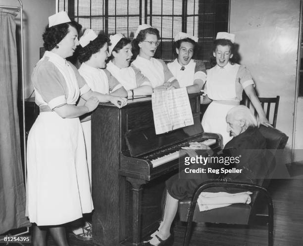 Catherine Mylrea, who is 103 years old, plays the piano for the nurses in her ward at St Francis' Hospital, East Dulwich, 10th August 1955. From left...