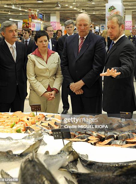 Norway's King Harald listens to an unidentified guide as he visits the fish department at a supermarket in Lisbon on May 28, 2008 with Norwegian...